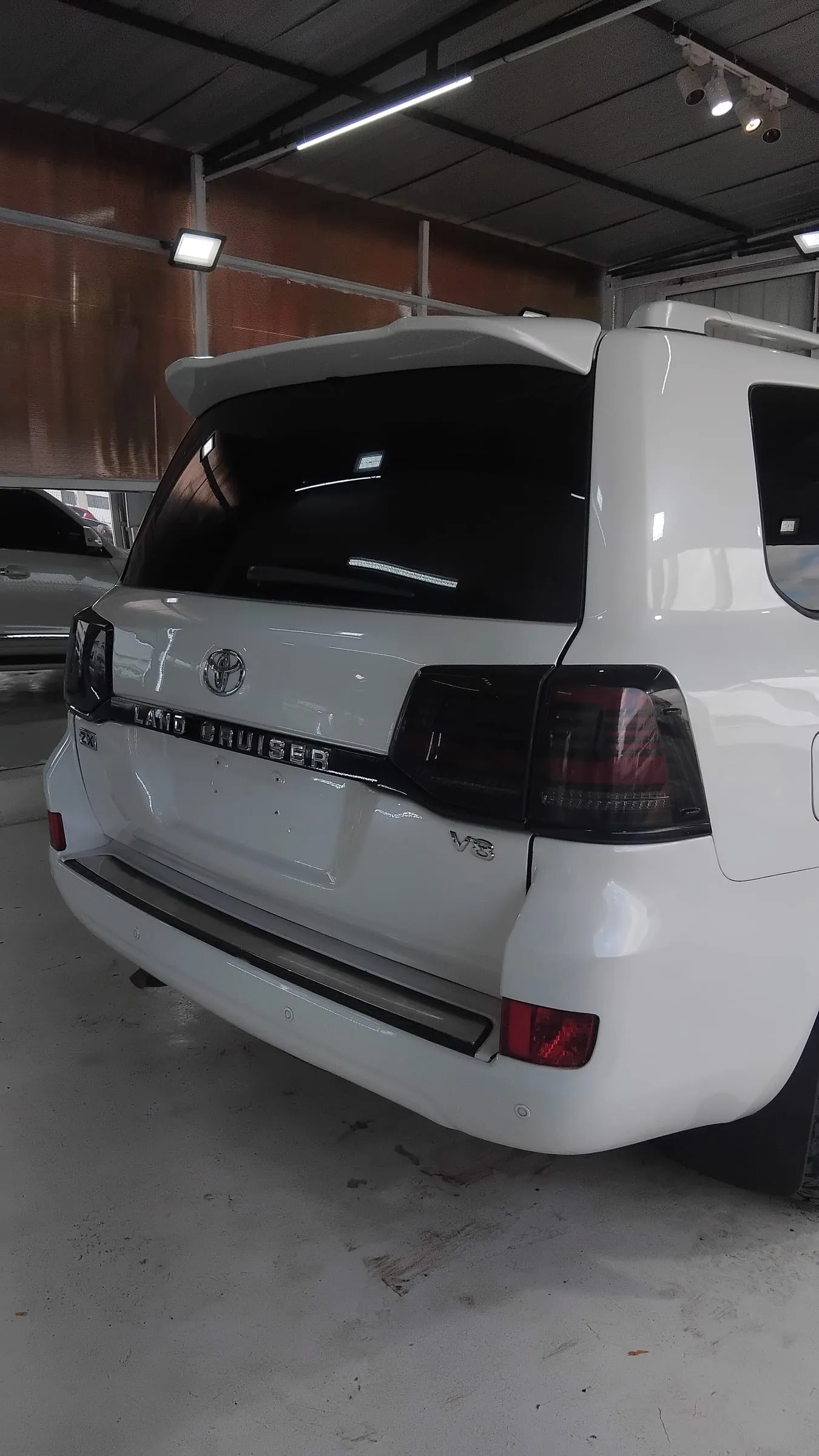 Rear three-quarter view of a white Toyota Land Cruiser V8 with smoked tail lights